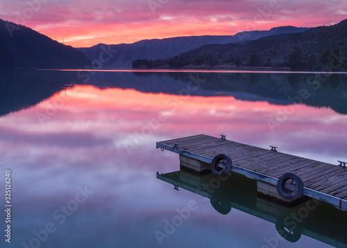 Reflejos de un embarcadero y el paisaje al atardecer en el rio Ebro en Almatret (Cataluña, España)