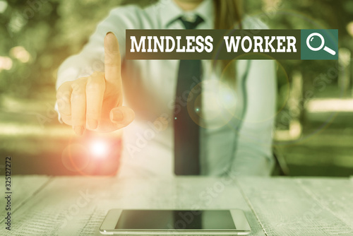 Word writing text Mindless Worker. Business photo showcasing Having no intelligent purpose Showing little attention Female business person sitting by table and holding mobile phone photo