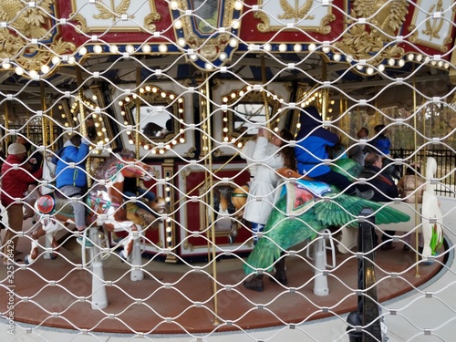 kids on merry go round through metal fence with holes