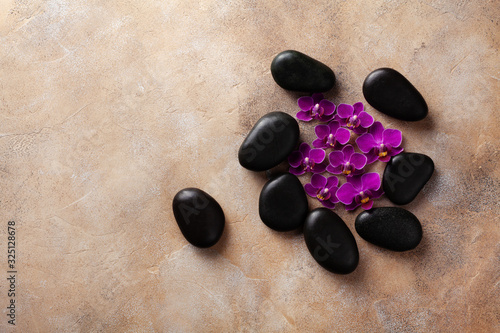 Spa composition with flowers and massage stone on brown background top view. Beauty treatment and relaxation concept. Flat lay. .