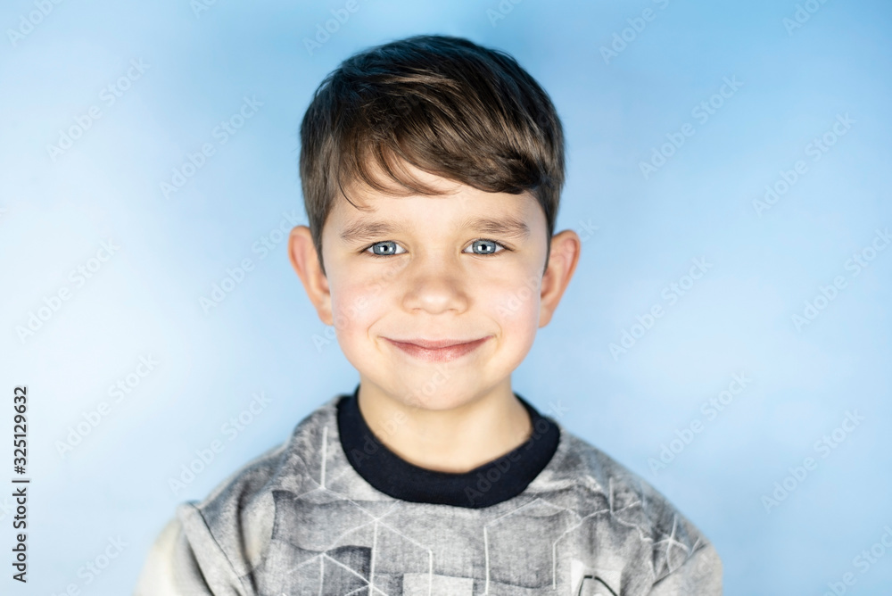 Portrait of young handsome boy on blue background. The boy is happy that his parents and brother and sister are very fond of him Portrait of young handsome boy on blue background. The boy is happy that his parents and brother and sister are very fond of him