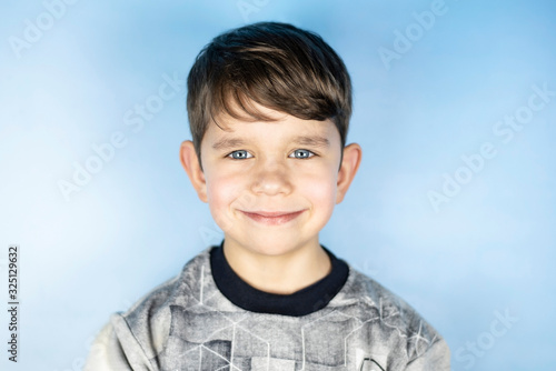 Portrait of young handsome boy on blue background. The boy is happy that his parents and brother and sister are very fond of him