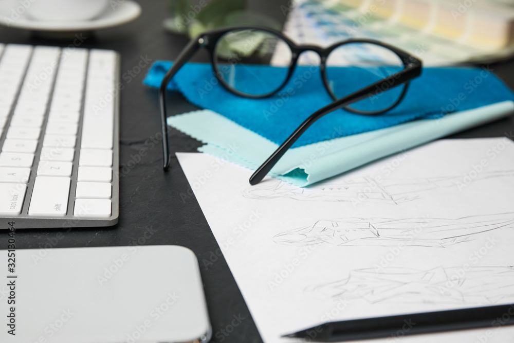 Sketches of clothes, smartphone and keyboard on black stone table, closeup. Designer's workplace Sketches of clothes, smartphone and keyboard on black stone table, closeup. Designer's workplace