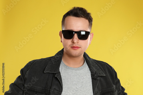 Young man wearing sunglasses on yellow background