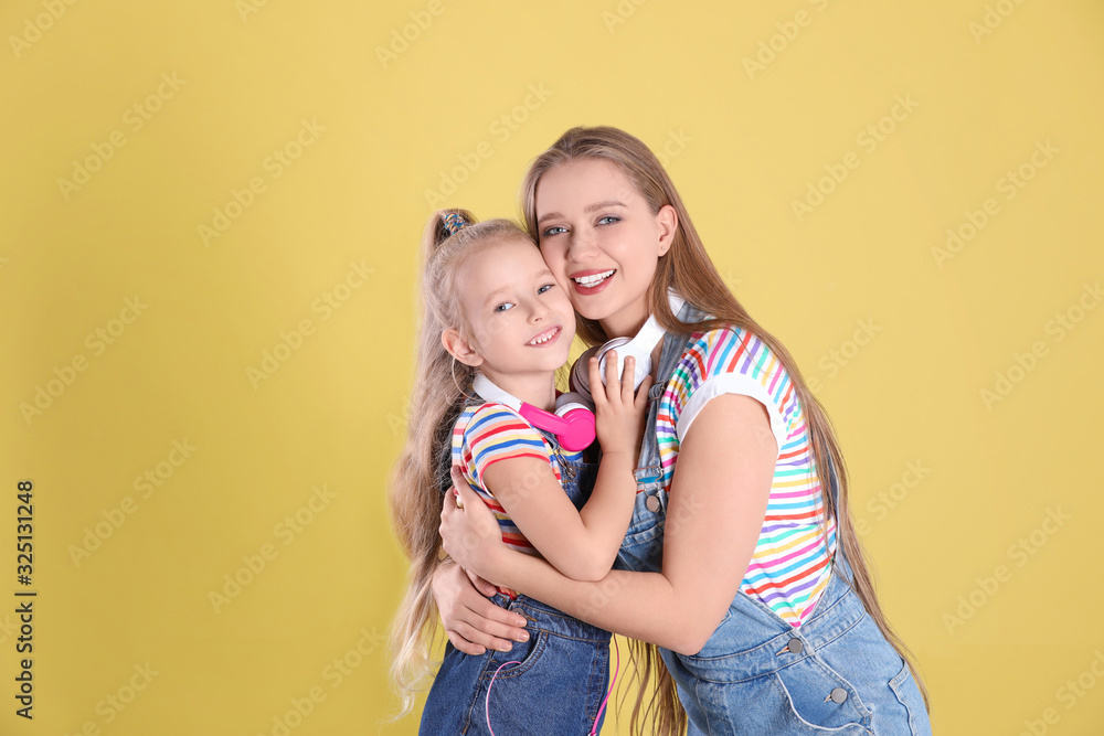 Happy mother and little daughter on yellow background Happy mother and little daughter on yellow background