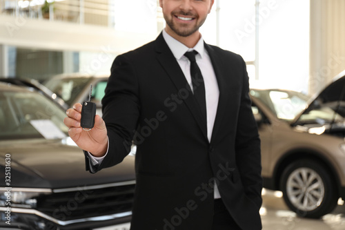 Salesman with key in modern car salon, closeup © New Africa