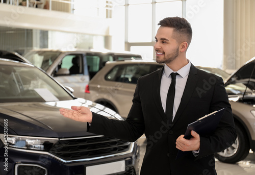 Young salesman with clipboard in modern car salon © New Africa