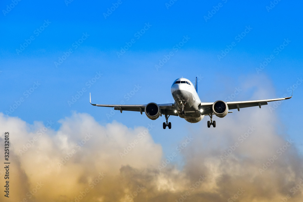 Passenger jet coming into land at an airport against blue sky and colourful clouds
