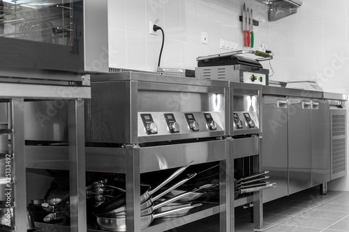Design of the working area of the commercial cafe kitchen with stainless steel equipments, hot shop, food industry.