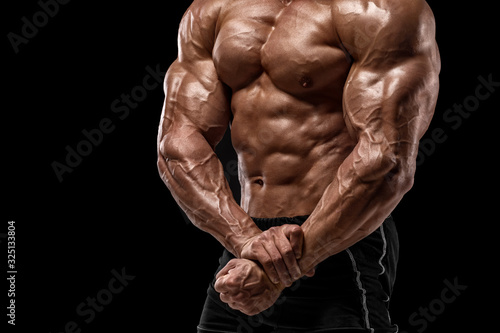 Muscular man showing muscles isolated on black background. Strong male naked torso abs