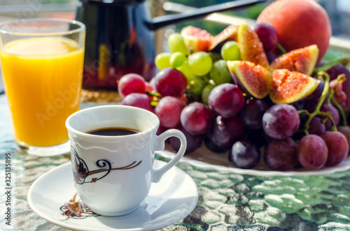 Breakfast table with coffee, orange juice, fruits and croissants