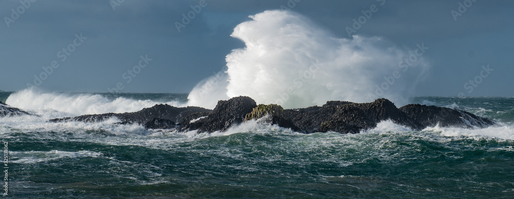 Massive waves crash over the rocks at Ballintoy Harbour, Causeway Coast, Northern Ireland
