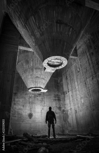 Fábrica de cemento abandonada durante la noche con silueta de persona explorándola. photo