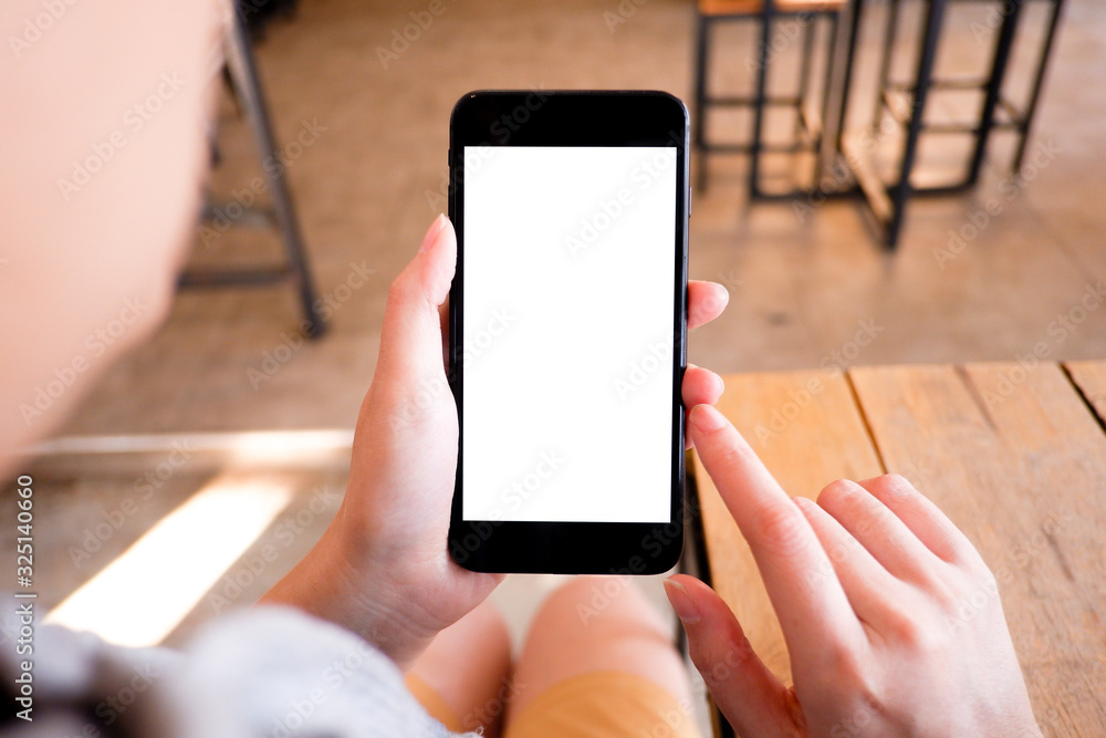 Mockup picture of business woman’s hands holding smart phone with white blank screen in modern place.