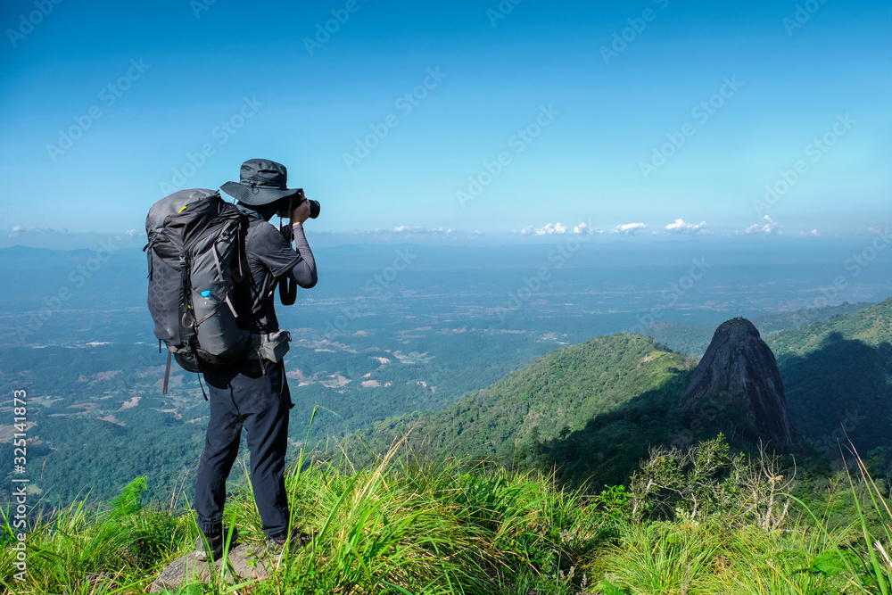 Hiker man standing and take a picture on hill of mountain and grenn tree