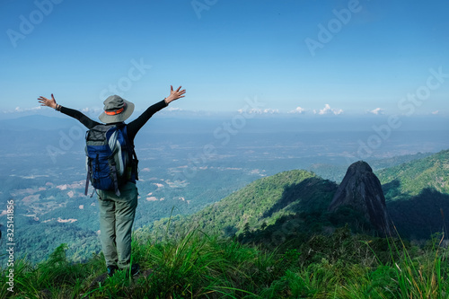 rear view of women stading on cliff and push hands up against mountain and tree