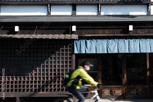 blur of a man ride bicycle ,wooden wall of window and old house in Japan. low key and soft focus.
