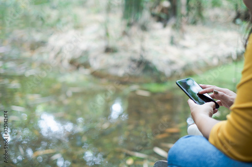 woman's hand holding and using smartphone, black screen with blur nature background. subject is blur.