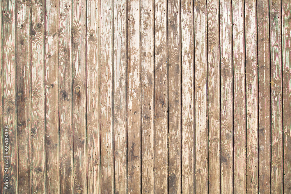 The background of the fence is made of old planed dark boards with a pronounced wood structure located vertically, texture design. The background of the fence is made of old planed dark boards with a pronounced wood structure located vertically, texture design.