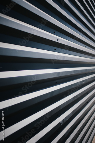 Abstract, high contrast image of metal wall with converging lines with highlights and shadows.