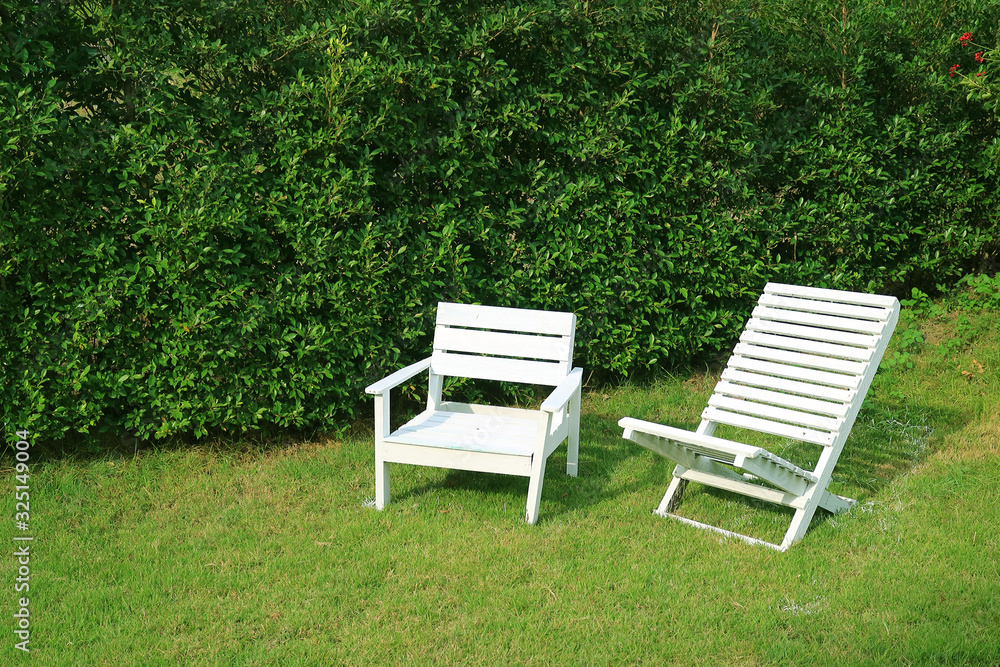 Two empty white colored wooden chairs in the sunshine garden Two empty white colored wooden chairs in the sunshine garden