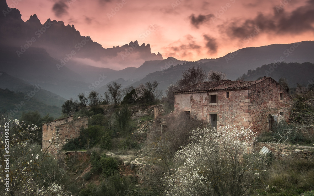 Atardecer con casa de campo en ruinas y la montaña de Montserrat al fondo en Cataluña, España. 