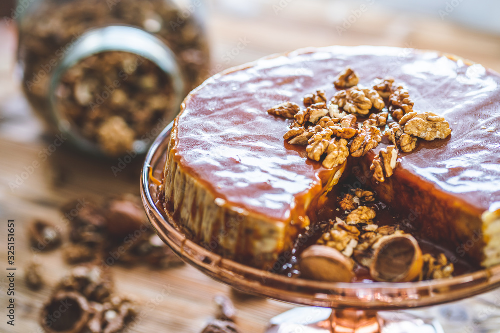 Sweet homemade chessecake with caramel topping and walnut nuts on wooden table. Tasty cake dessert.