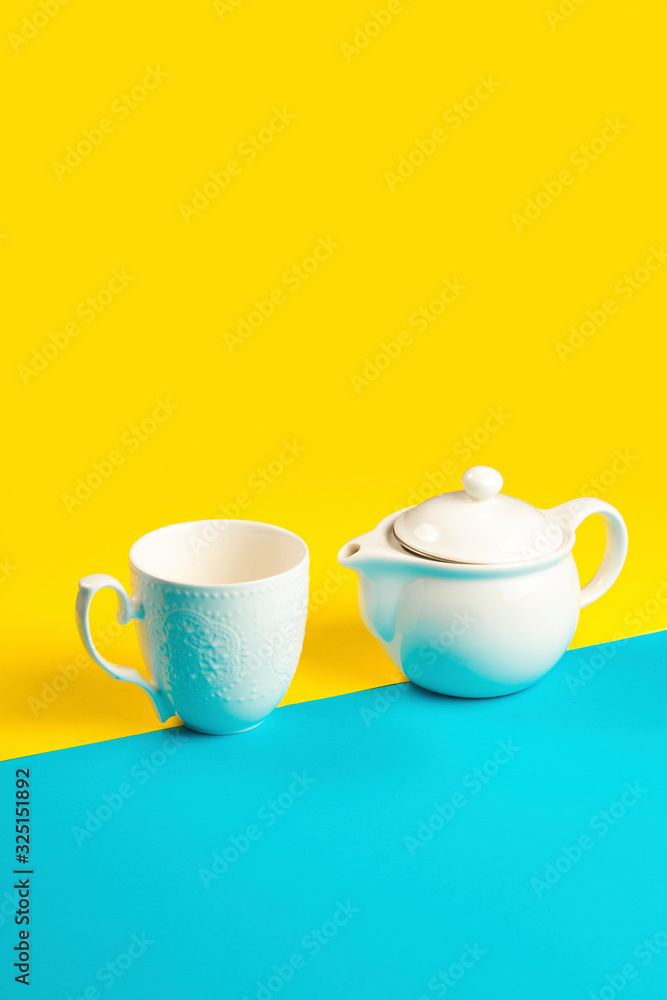 Tea pot and tea mug on a yellow and blue background Tea pot and tea mug on a yellow and blue background
