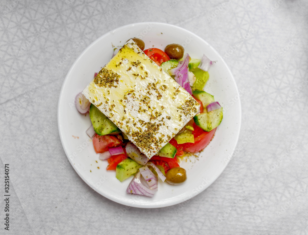 original feta cheese in Greek salad plate, top view close up