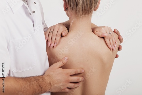 Osteopath does back and shoulder massage to a girl