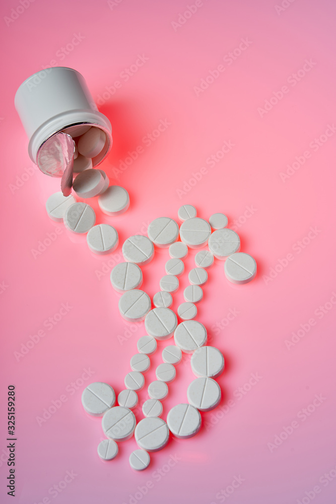 White pills are laid in the dollar sign on a pink background.White pills fell out of a still bottle. Pharmaceutical business concept. White pills are laid in the dollar sign on a pink background.White pills fell out of a still bottle. Pharmaceutical business concept.
