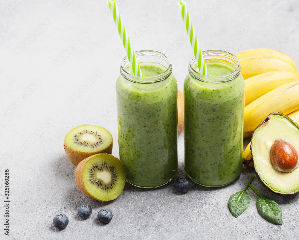 Healthy green smoothie with banana, spinach, berries, avocado and kiwi in a glass bottles Healthy green smoothie with banana, spinach, berries, avocado and kiwi in a glass bottles