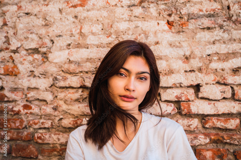 Young latin woman against brick wall. Young latin woman against brick wall.