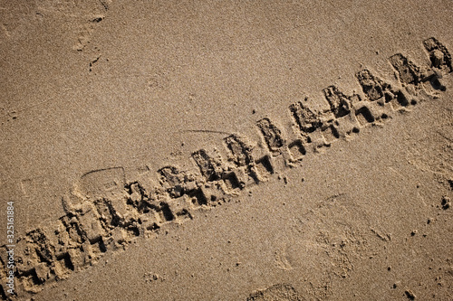 Tyre tracks on a golden sand beach. Puglia region, Italy