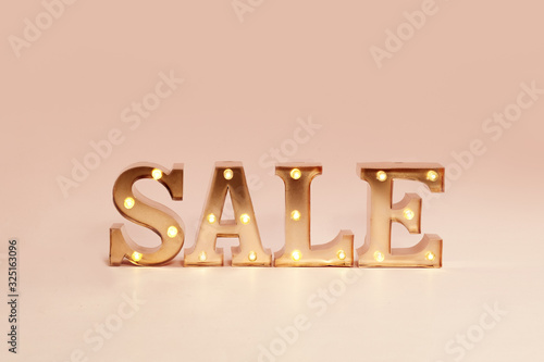 advertisement Sale illuminated metal letters at pastel background