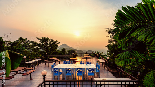 High angle viewpoint for watching the beautiful nature landscape colorful sky during the sunset. Table and chairs on the terrace for dining of the restaurant on the mountain, Chon Buri, Thailand, 16:9