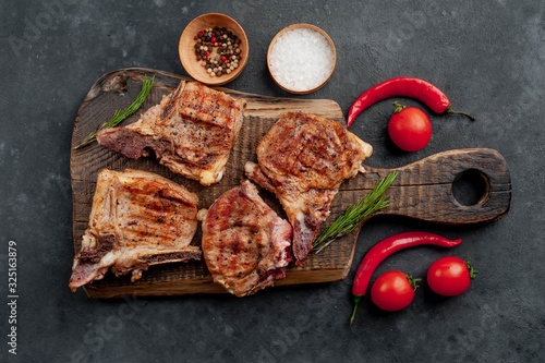 grilled beef steaks with spices on a cutting board on a stone background 
