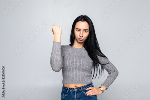Принти на полотні Portrait of young dominating brunette woman showing fist on gray background