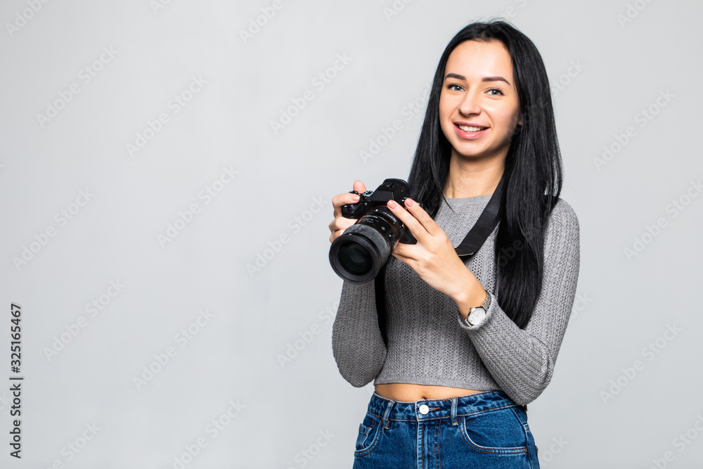 Attractive brunette aims her camera. composing a photograph in studio, isolated on gray background Attractive brunette aims her camera. composing a photograph in studio, isolated on gray background
