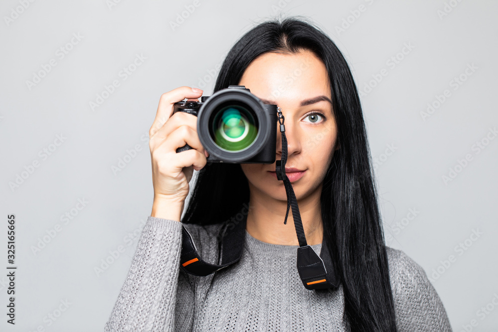 Portrait of a young woman taking pictures on the camera, isolated on gray background Portrait of a young woman taking pictures on the camera, isolated on gray background
