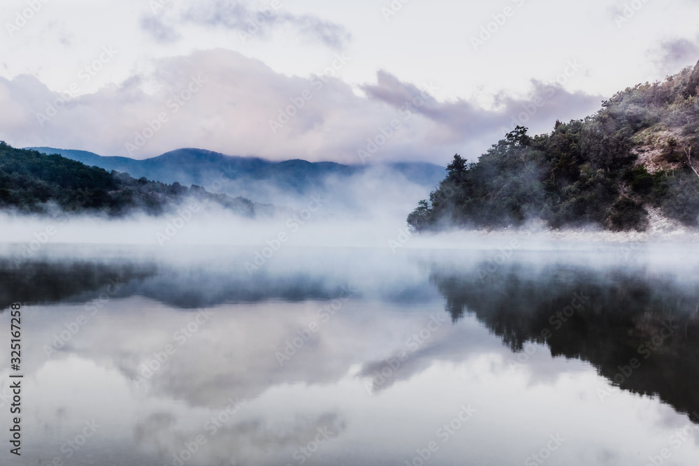 Early morning on a mountain lake. Steam over the water. Blue mountains in the distance. Early morning on a mountain lake. Steam over the water. Blue mountains in the distance.