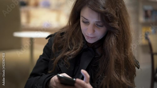 Wallpaper Mural Middle shot of happy smiling female brown hair holding a phone on blurred beige background indoors. Close up face of brunette woman in black clothes cyber chatting Torontodigital.ca