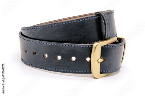 sample of classic leather men's belt with metal shiny buckle handmade in black twisted into a ball, the concept of manual craft,close up