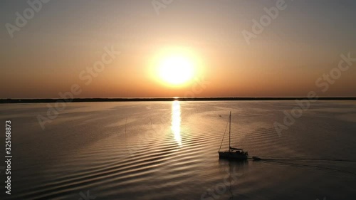 Yacht sailing on becalmed sea at sunset
