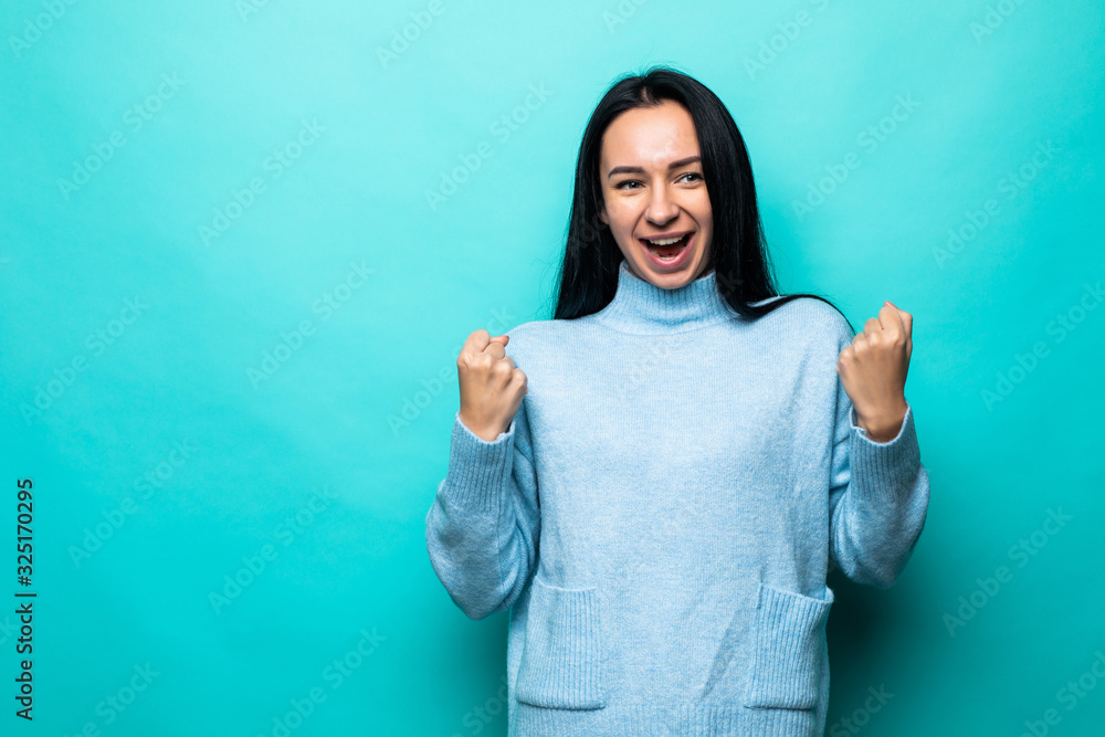 Excited young woman standing isolated over blue background make winner gesture. Excited young woman standing isolated over blue background make winner gesture.