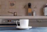 White coffee or teacup on a wooden surface of dark gray color on a blurred background of the kitchen