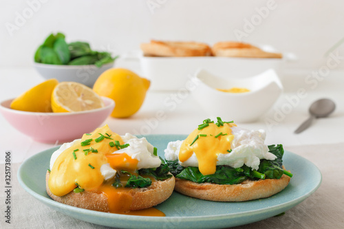 Fotografia Eggs Florentine, English muffins, grilled ham, poached eggs, Hollandaise sauce, chive herbs, lemon, cup of coffee
