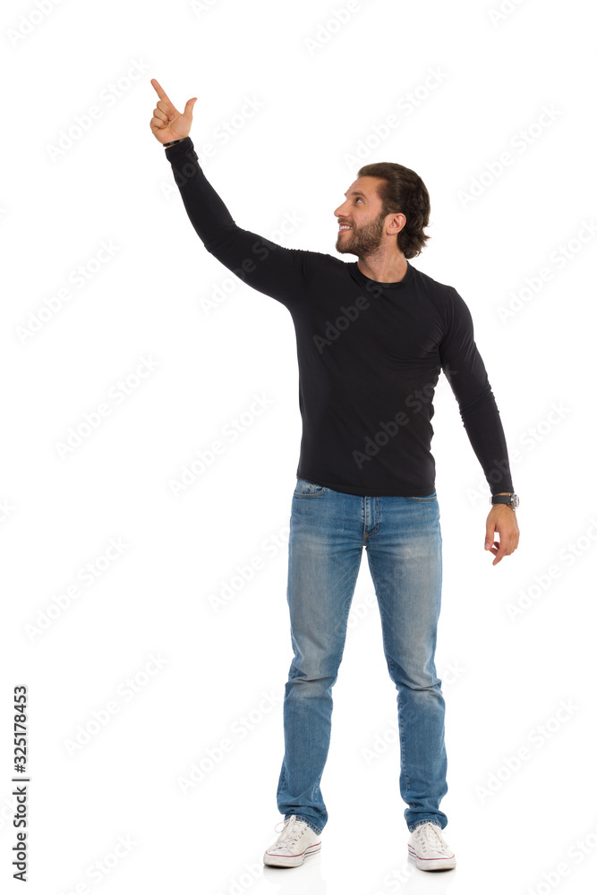 Standing Man Is In Black Blouse And Jeans Is Pointing Up And Looking Up. Front View. Standing Man Is In Black Blouse And Jeans Is Pointing Up And Looking Up. Front View.