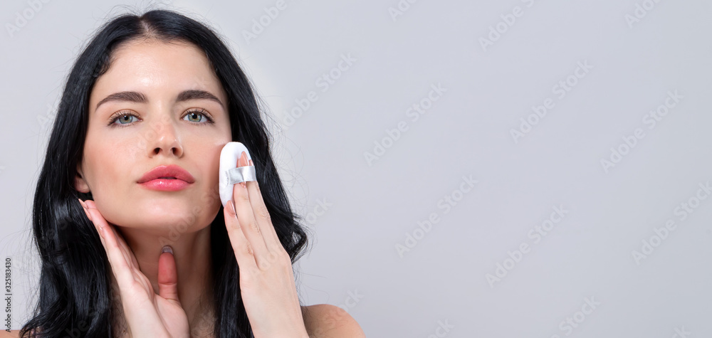 Beautiful young woman with makeup kit on a gray background Beautiful young woman with makeup kit on a gray background