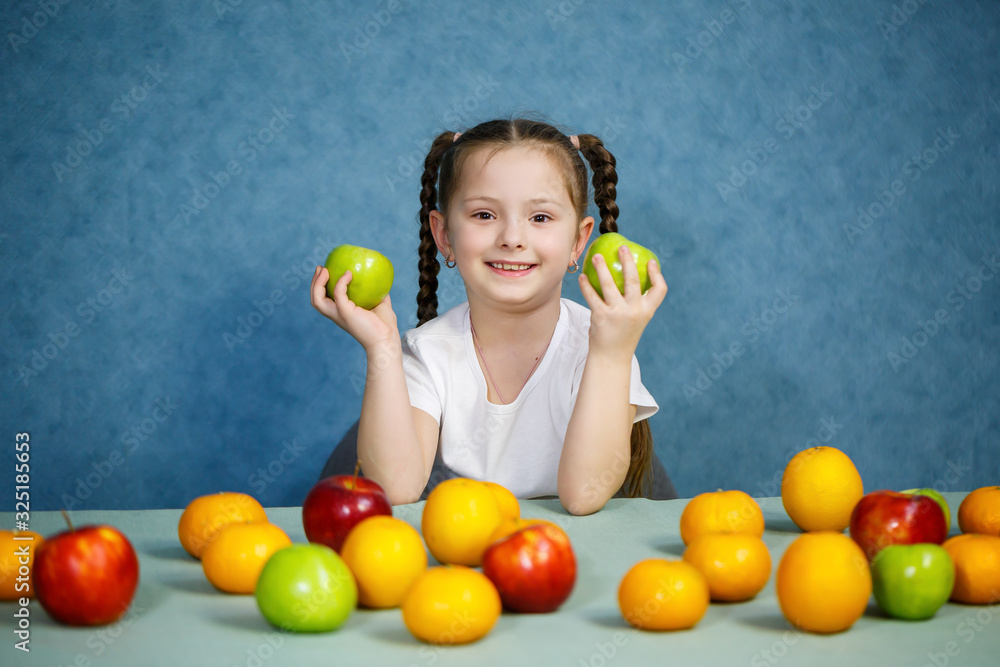 Fototapeta premium Little girl in white T-shirt plays and poses with fruit